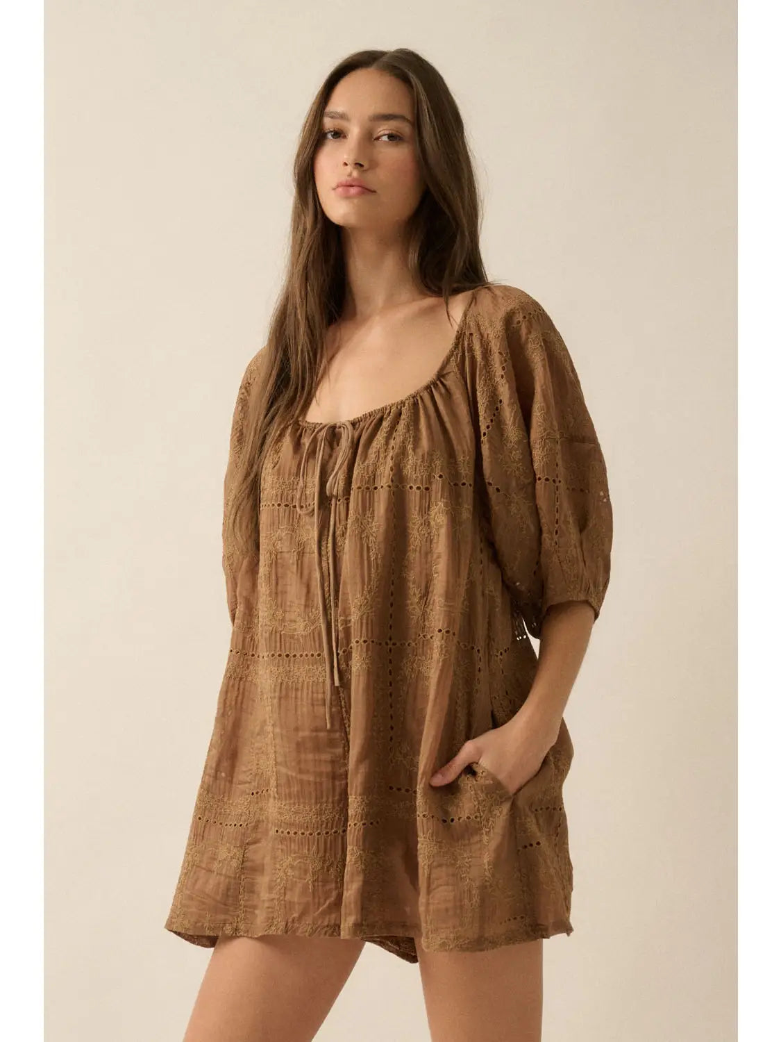 Woman wearing a brown romper against a beige background